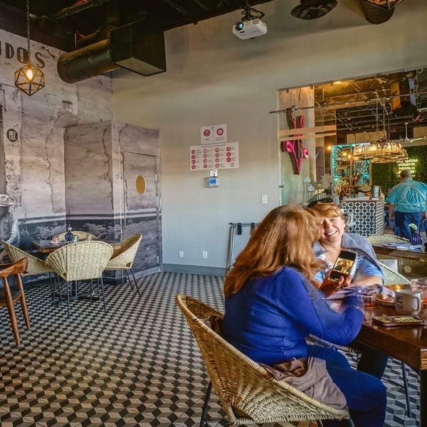 Patrons enjoying a meal in a restaurant with a large mural and checkered floor.