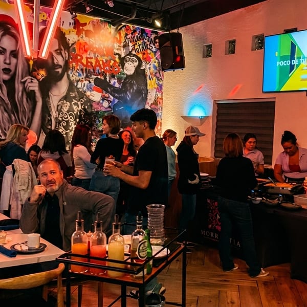 Diners enjoying a lively restaurant with colorful wall art, a buffet, and a TV playing music.